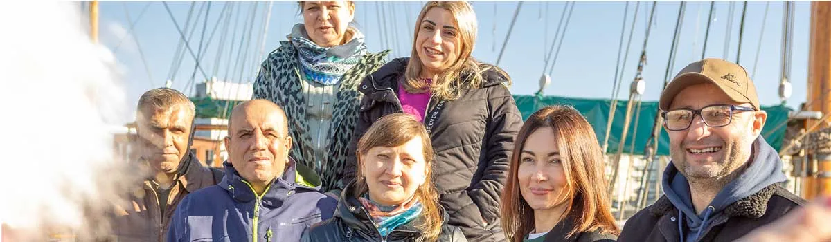 Eine Gruppe von Menschen formieren sich auf einem Segelboot für ein Gruppenfoto.