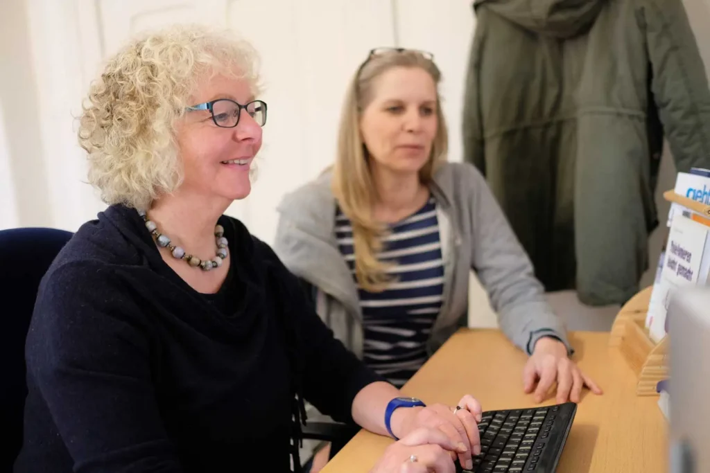 Zwei Frauen am Tisch, die am Computer arbeiten