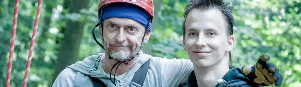 Zwei Männer kumpelhaft nebeneinader. Im Hintergrund Wald