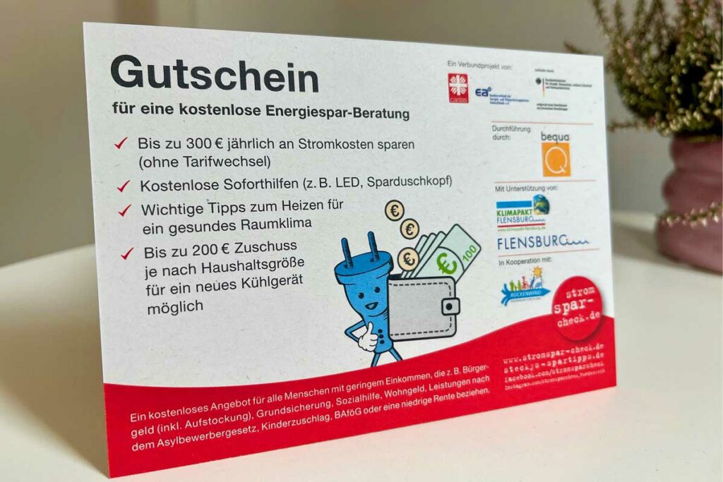 Eine Gutschein in Form einer Visitenkarte für eine kostenlose Energie-Beratung steht auf einem Tisch