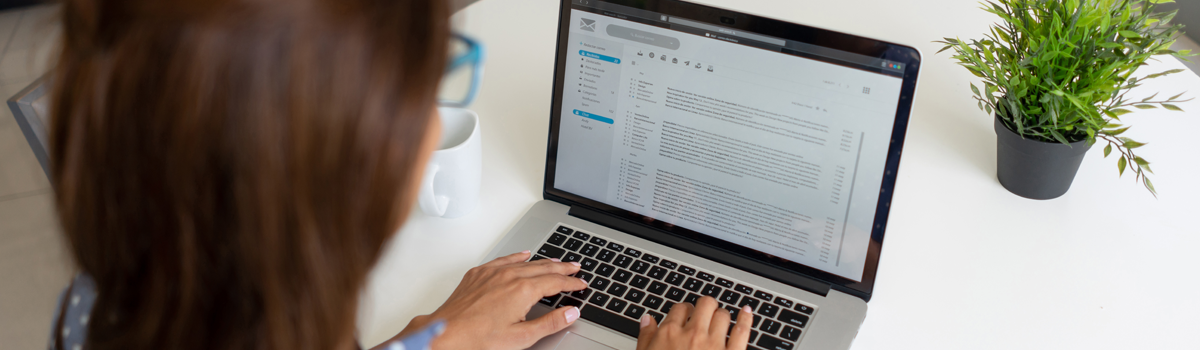 Eine Person sitzt am Laptop und tippt auf der Tastatur